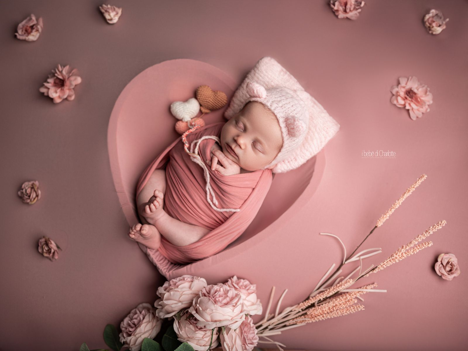 Neonata in un cuore rosa tra fiori e cuoricini