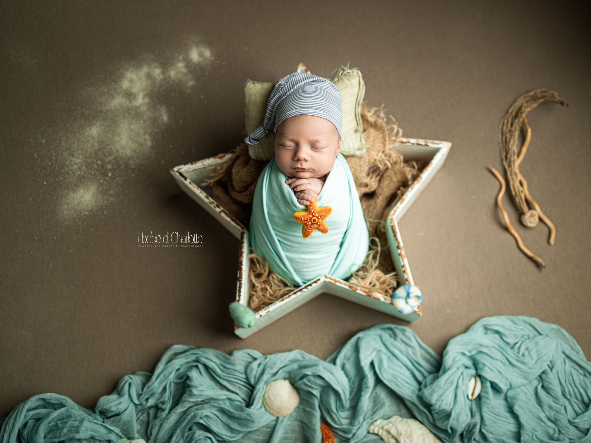 Neonato avvolto in fasce color menta con stella marina